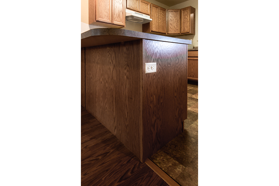 An electrical outlet is on the outside of a kitchen island, allowing someone to plug in devices without reaching over a counter.